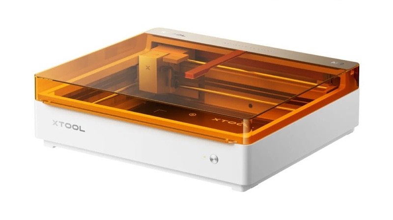 xTool M2 vu de trois quarts : socle blanc, capot orange translucide laissant voir la tête laser et le portique